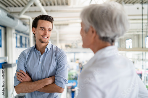 Smiling businessman talking to senior businesswoman in a factory photo
