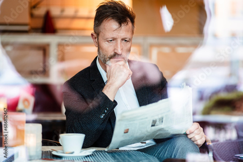 Obraz na płótnie Portrait of pensive mature businessman reading newspaper in a coffee shop w salonie