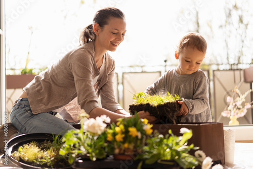 Mother and daughter planting flowers together on balcony photo