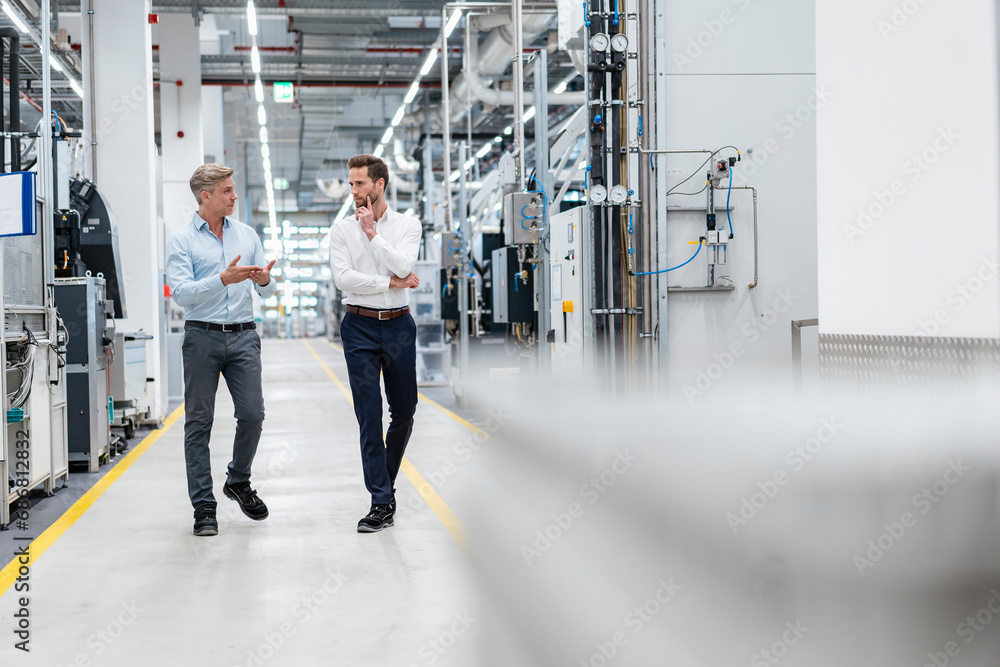 Two businessmen talking in a modern factory