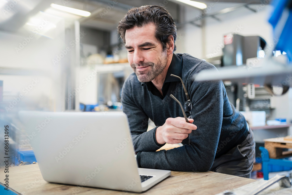 Businessman using laptop in a factory