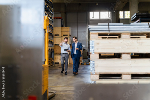 Businessman and colleague inspecting warehouse while walking at factory © tunedin