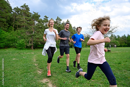 Cheerful family running on meadow against trees in forest