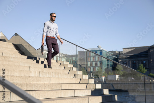 Businessman wearing sunglasses walking downstairs © tunedin