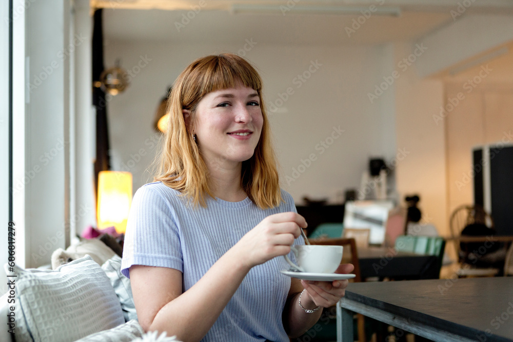 Portrait of strawberry blonde young woman with nose piercing with cup of coffee in a cafe Portrait of strawberry blonde young woman with nose piercing with cup of coffee in a cafe