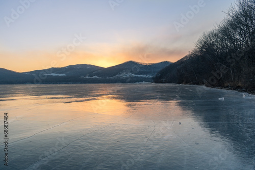  Winter landscape. The surface of the ice is bound by ice  with a perfectly smooth  mirror-like appearance. Sunset in winter over the lake. 