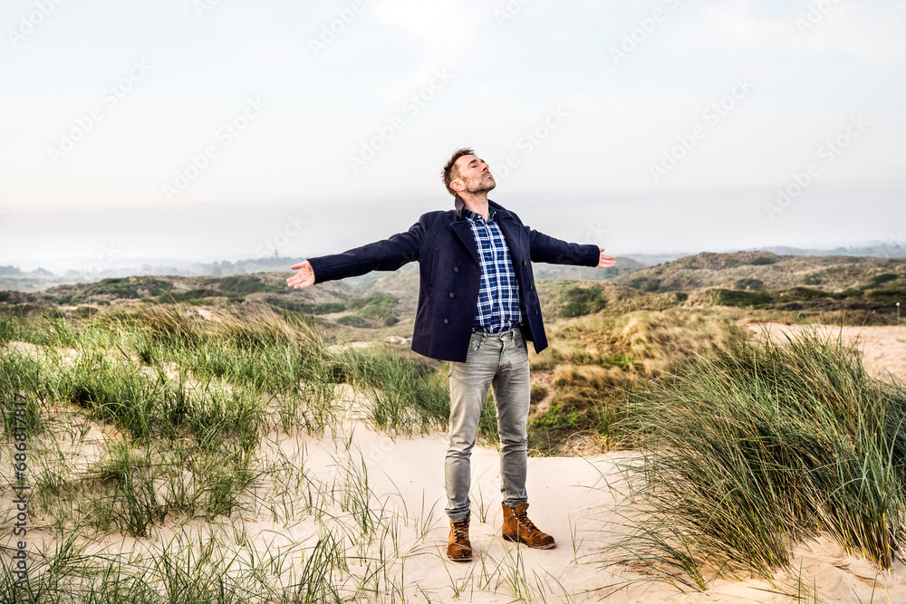 Man standing in dunes with outstretched arms