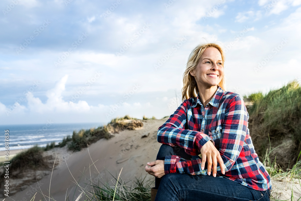 Smiling woman sitting in dunes Smiling woman sitting in dunes