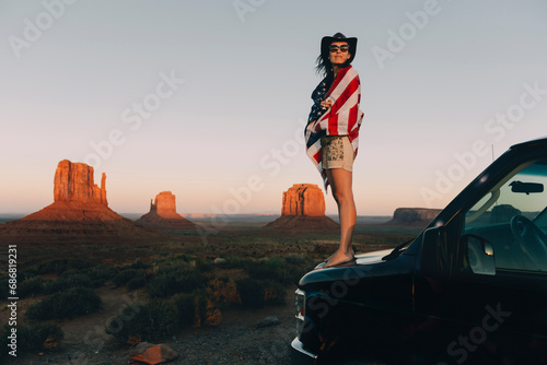 USA, Utah, Monument Valley, Woman with United States of America flag enjoying the sunset in Monument Valley