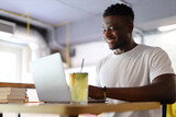 Happy young businessman working on a laptop in a modern office or cafe, exuding confidence and success.