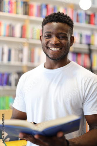 Joyful young student in a university library, confidently choosing books, exuding happiness and confidence.