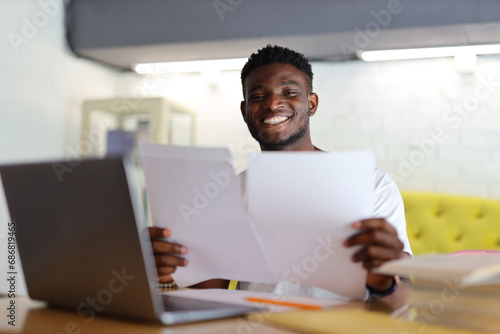 Happy businessman in an office, reading a document, exuding joy and success in professional achievements.