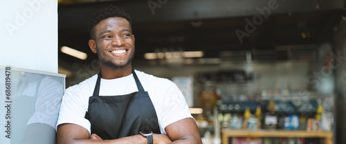 Cheerful entrepreneur in an apron, standing with crossed arms, exuding confidence and positivity in a successful restaurant.