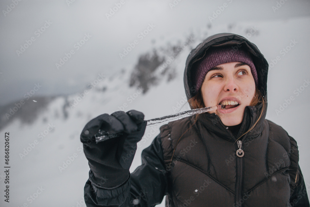Austria, Kitzbuehel, portrait of young woman biting icicle Austria, Kitzbuehel, portrait of young woman biting icicle