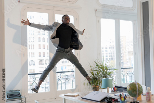 Happy young businessman jumping in the air in his office © tunedin