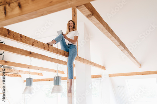 Carefree young woman sitting on ceiling joist © tunedin