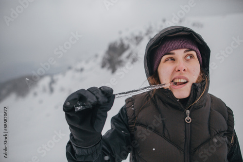 Austria, Kitzbuehel, portrait of young woman biting icicle photo