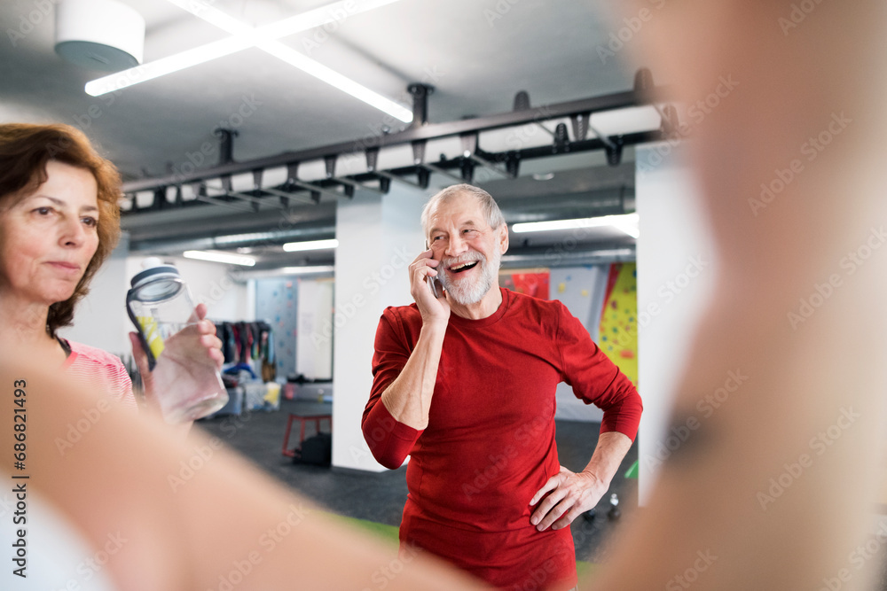 Obraz premium Fit senior man with smart phone in gym