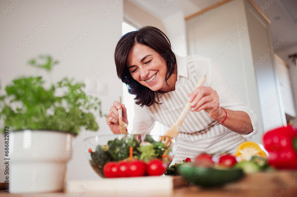 Mature woman preparing salad in her kitchen Mature woman preparing salad in her kitchen