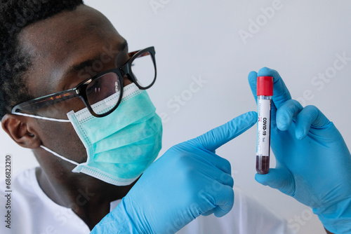 Close-up of afro doctor showing coronavirus blood sample against white background