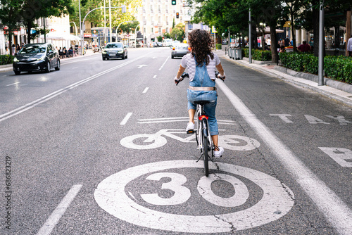 Mature woman riding on bicycle lane in city photo