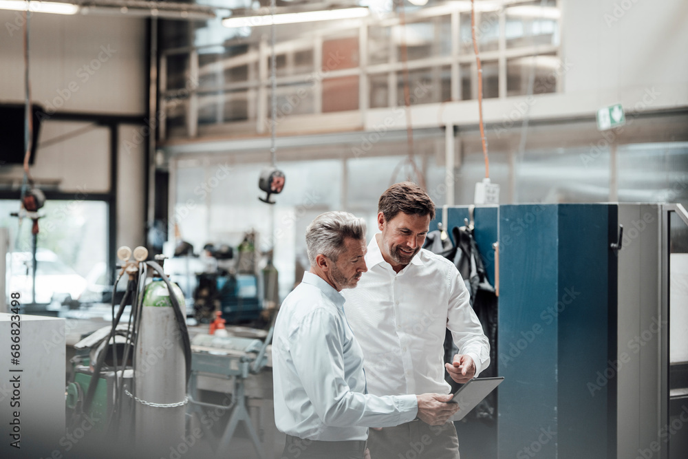 Businessman discussing with male colleague over digital tablet in industry