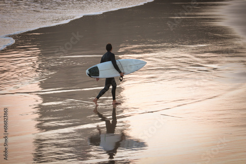 Silhouette and reflection of surfer with surfboard on a beach at sunset. Surfer and ocean photo