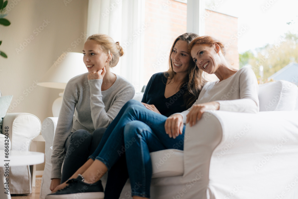 Happy mother with two teenage girls on couch at home Happy mother with two teenage girls on couch at home