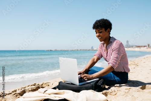 Photography Woman sitting on the beach while working with the laptop