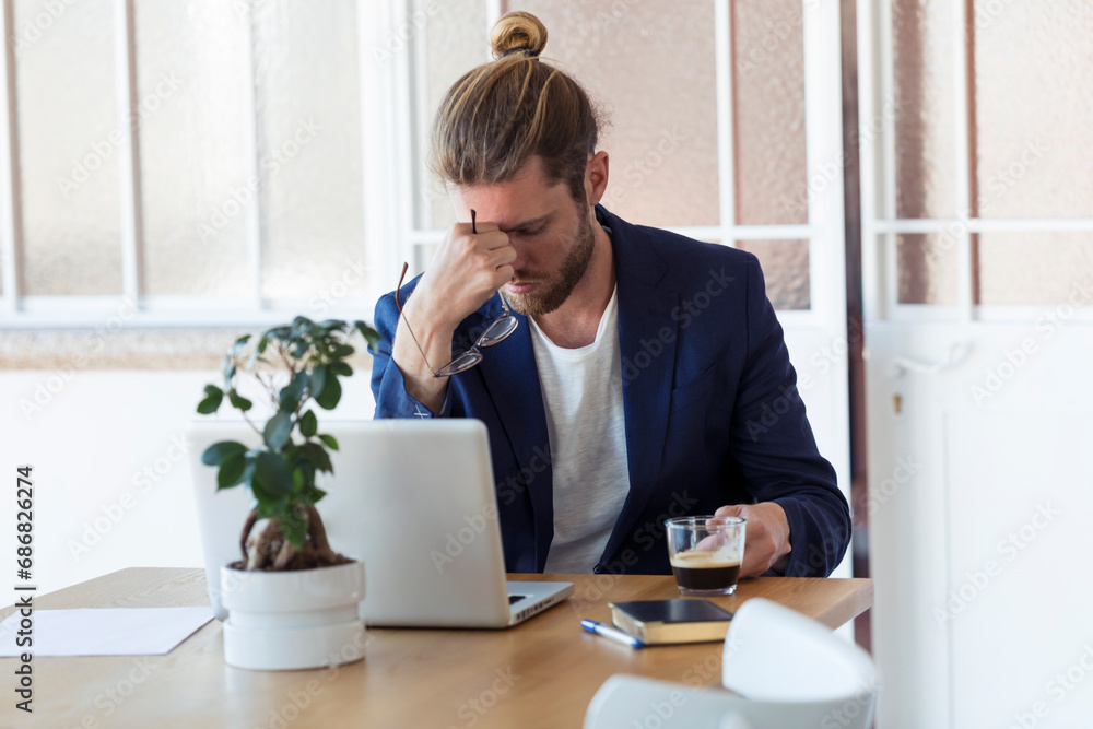 Tired businessman sitting at table in office Tired businessman sitting at table in office