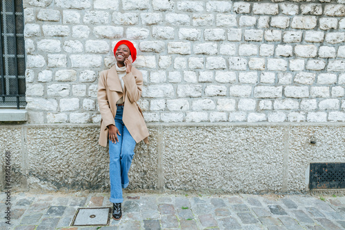 Young woman in Paris leaning against wall and talking on the phone © tunedin
