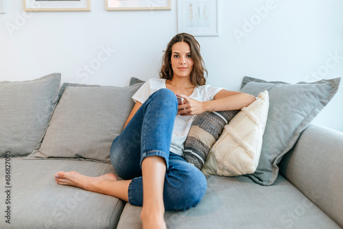 Portrait of young woman sitting on sofa with cell phone