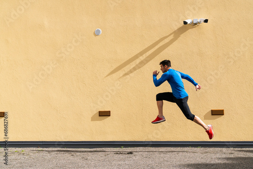 Sportive man exercising at yellow wall with CCTV camera