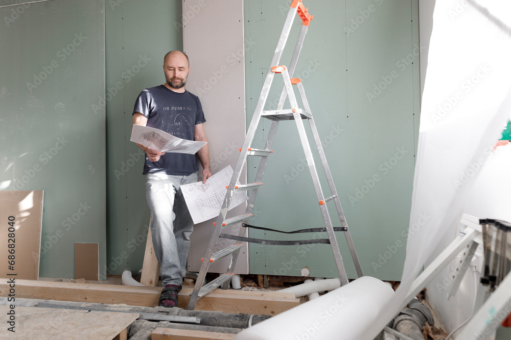 Man on construction site at home studying plan