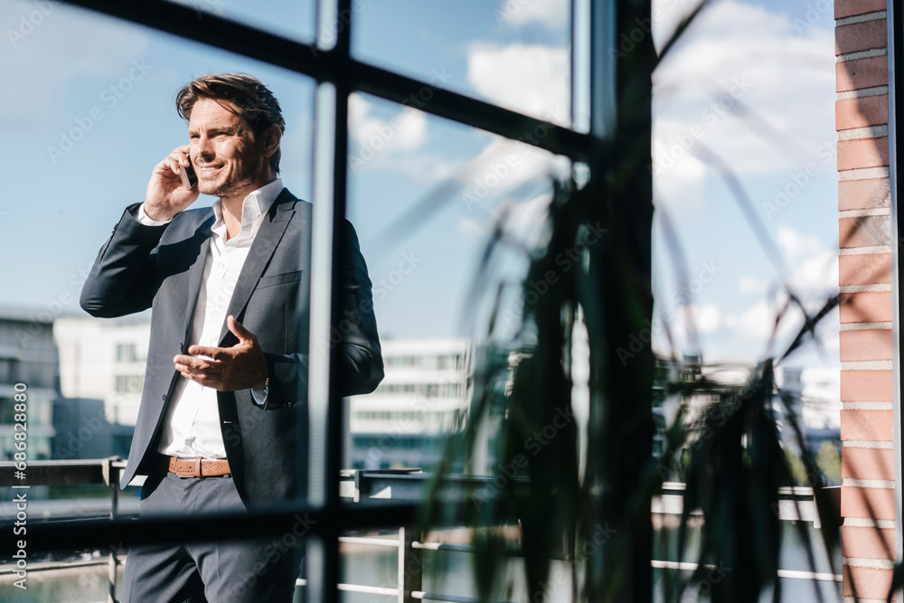 Businessman making a phone call, standing on balcony Businessman making a phone call, standing on balcony