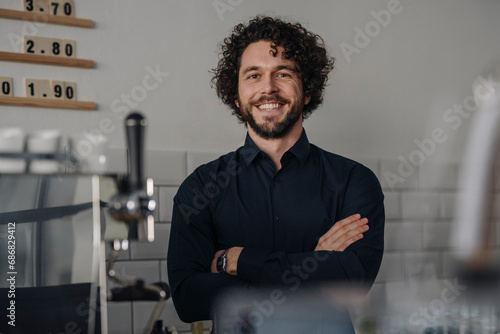 Proud coffee shop owner standing behind counter photo