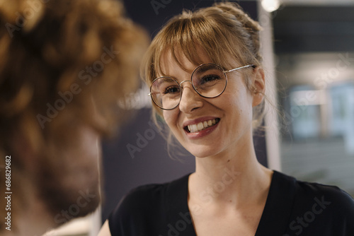 Portrait of smiling businesswoman looking at businessman in offce photo