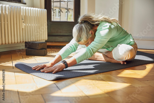 Woman exercising on exercise mat over floor in living room