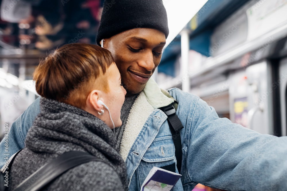 Portrait of young couple sharing earbuds on a subway Portrait of young couple sharing earbuds on a subway