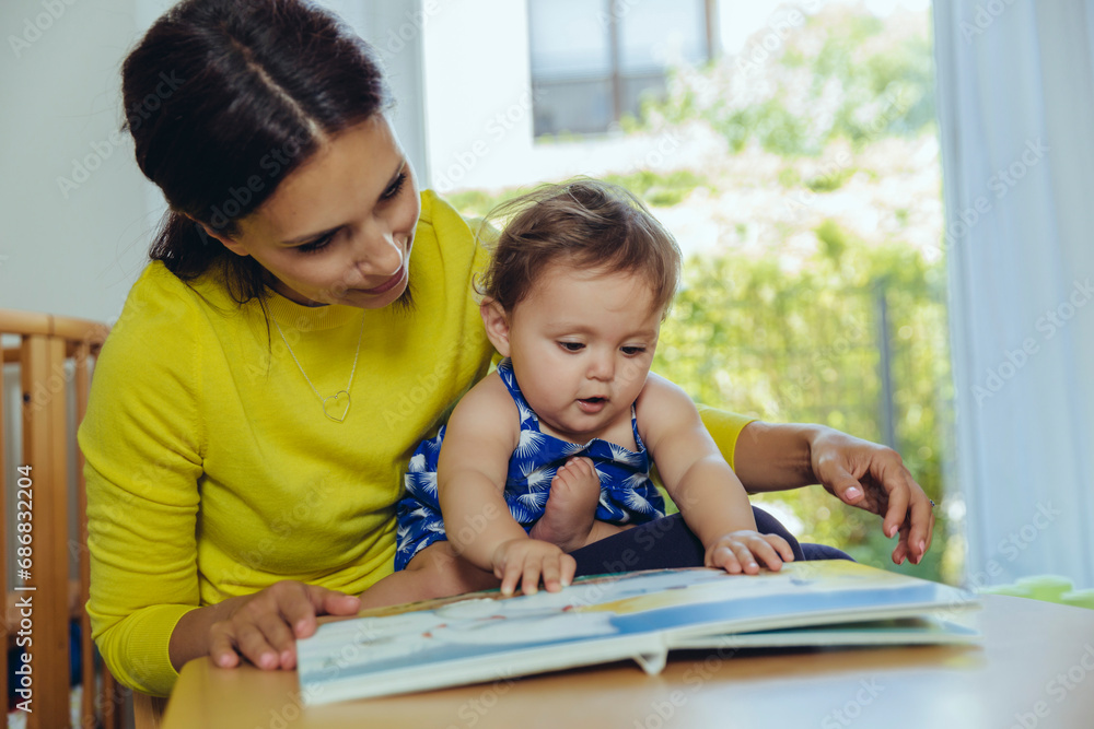 Mother and baby daughter looking at children?s book Mother and baby daughter looking at children?s book