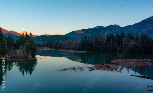 Canadian Mountain Landscape, peaceful river with green trees. Sunny Sunset.