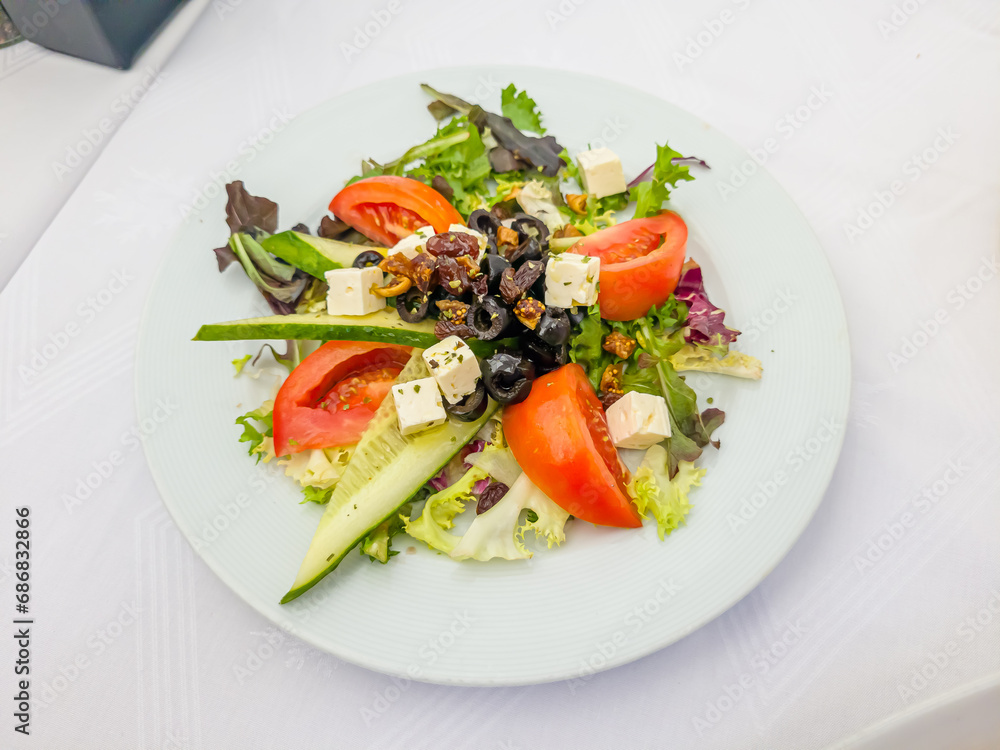 A Greek salad with cucumbers, tomatoes, olives and feta cheese is on a plate in the restaurant A Greek salad with cucumbers, tomatoes, olives and feta cheese is on a plate in the restaurant