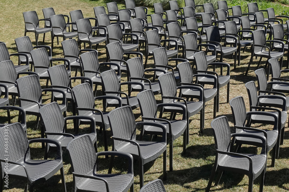 Naklejka premium rows of black plastic chairs outdoor furniture on lawn
