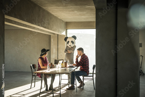 Woman with panda mask watching colleagues in office