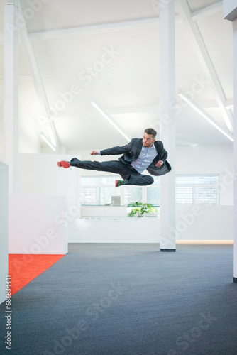 Businessman jumping mid-air on office floor