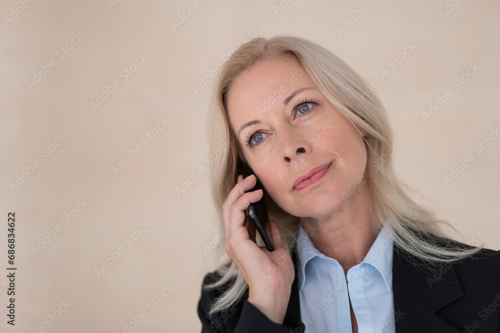 Close-up of female entrepreneur talking over mobile phone against wall in office Close-up of female entrepreneur talking over mobile phone against wall in office