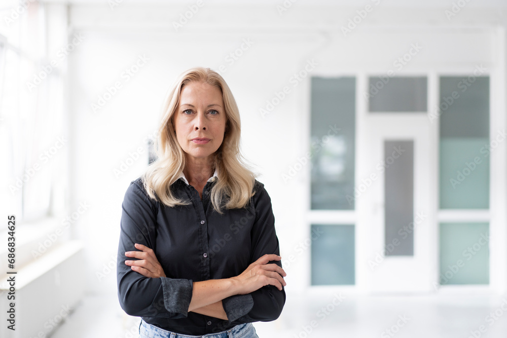 Confident female professional with arms crossed standing in home office Confident female professional with arms crossed standing in home office