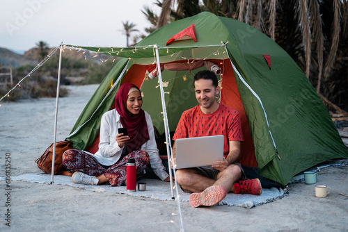Young woman wearing Hijab and man using laptop at a tent