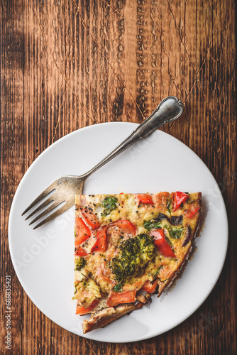 Slice of vegetable frittata on white plate