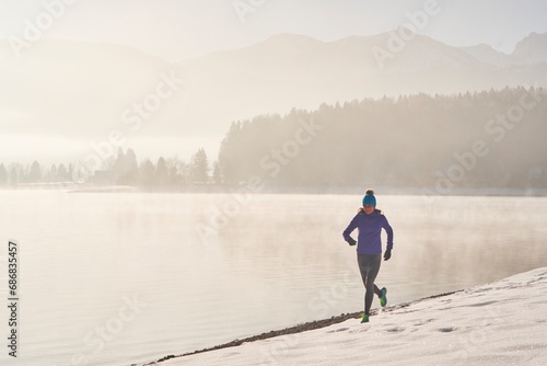Germany, Bavaria, Lake Walchen, woman jogging in winter